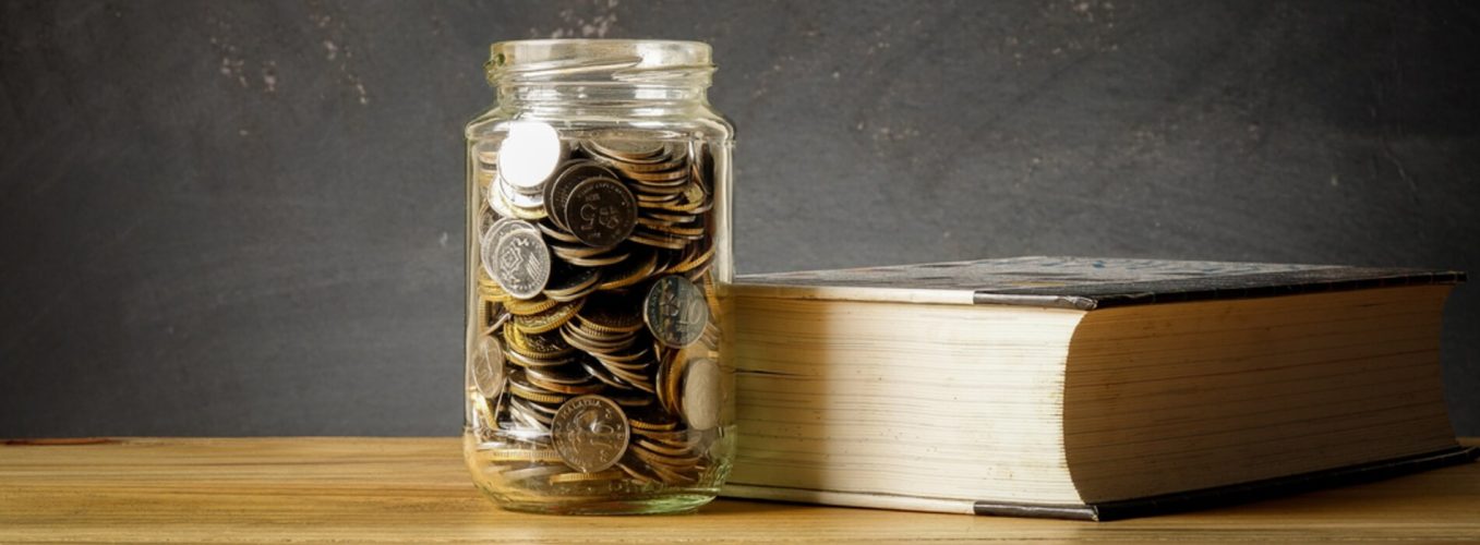 This image shows a jar of coins next to a book.