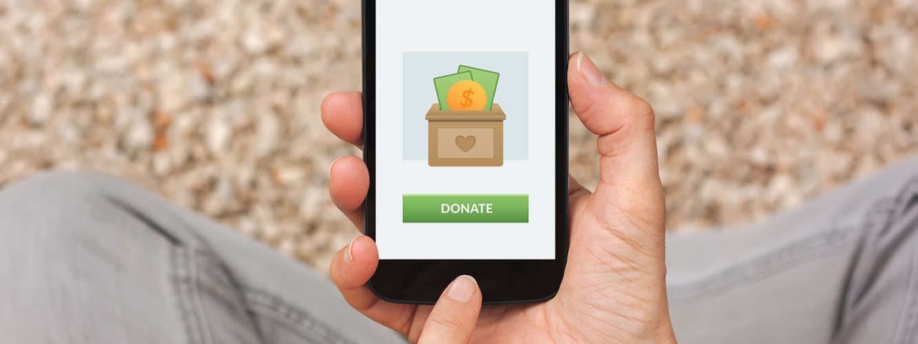 A hand holds a smartphone with a donate button on the screen.