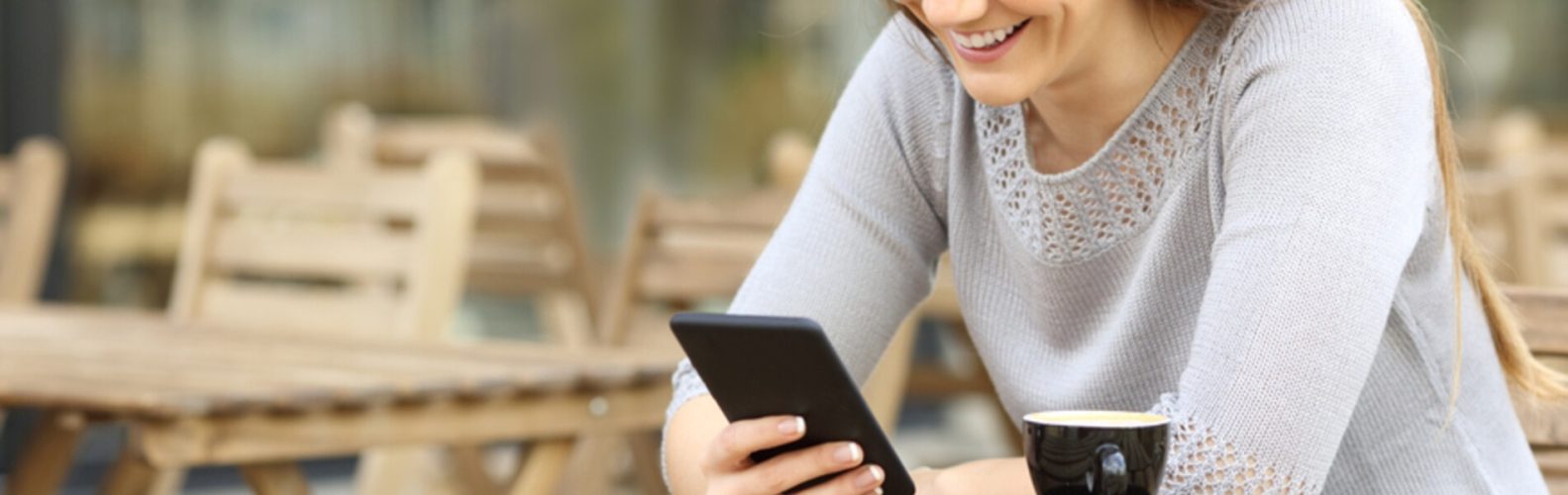 A woman smiles at a text she just received on her phone.