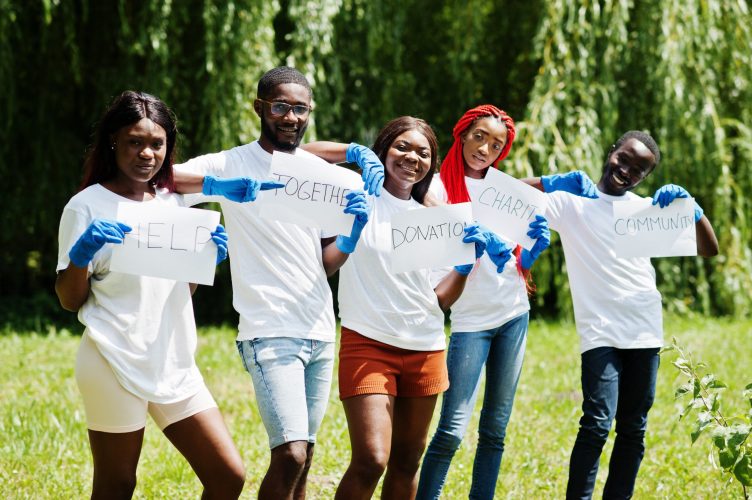 Group of happy african volunteers hold blank board in park. Africa volunteering, charity, people and ecology concept.