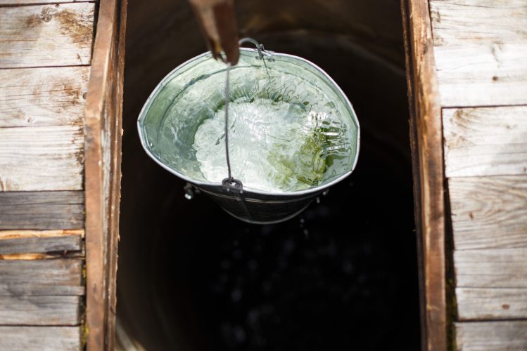 Blue bucked inside water well. water well with an old iron bucket