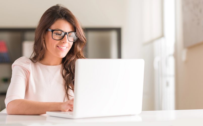 A fundraising professional smiles at her computer as she composes a fundraising email.