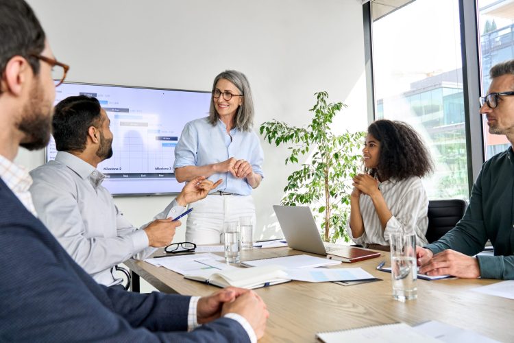 International executive team people having board meeting discussing project results. Diverse employees group working with senior leader brainstorming in office meeting room at presentation training.