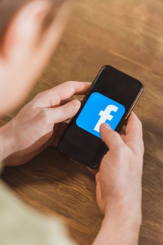 Man using smartphone with facebook logo icon on screen